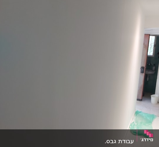 קיר גבס צבוע בלבן עם רצפת עץ